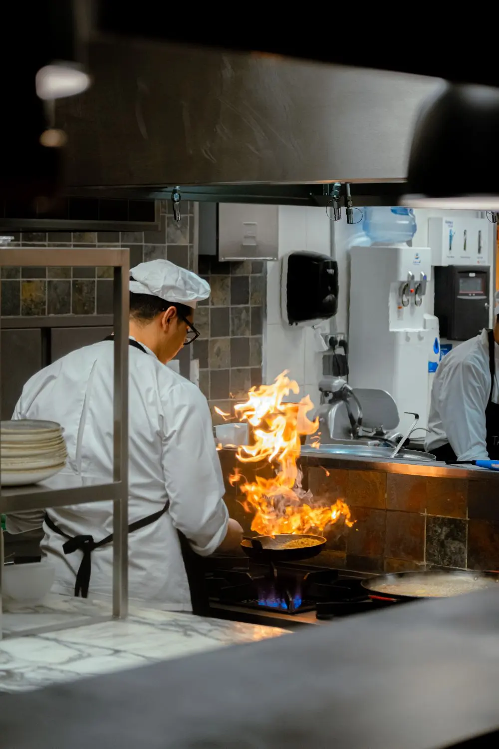 La chef cocinando con llama en la cocina del restaurante