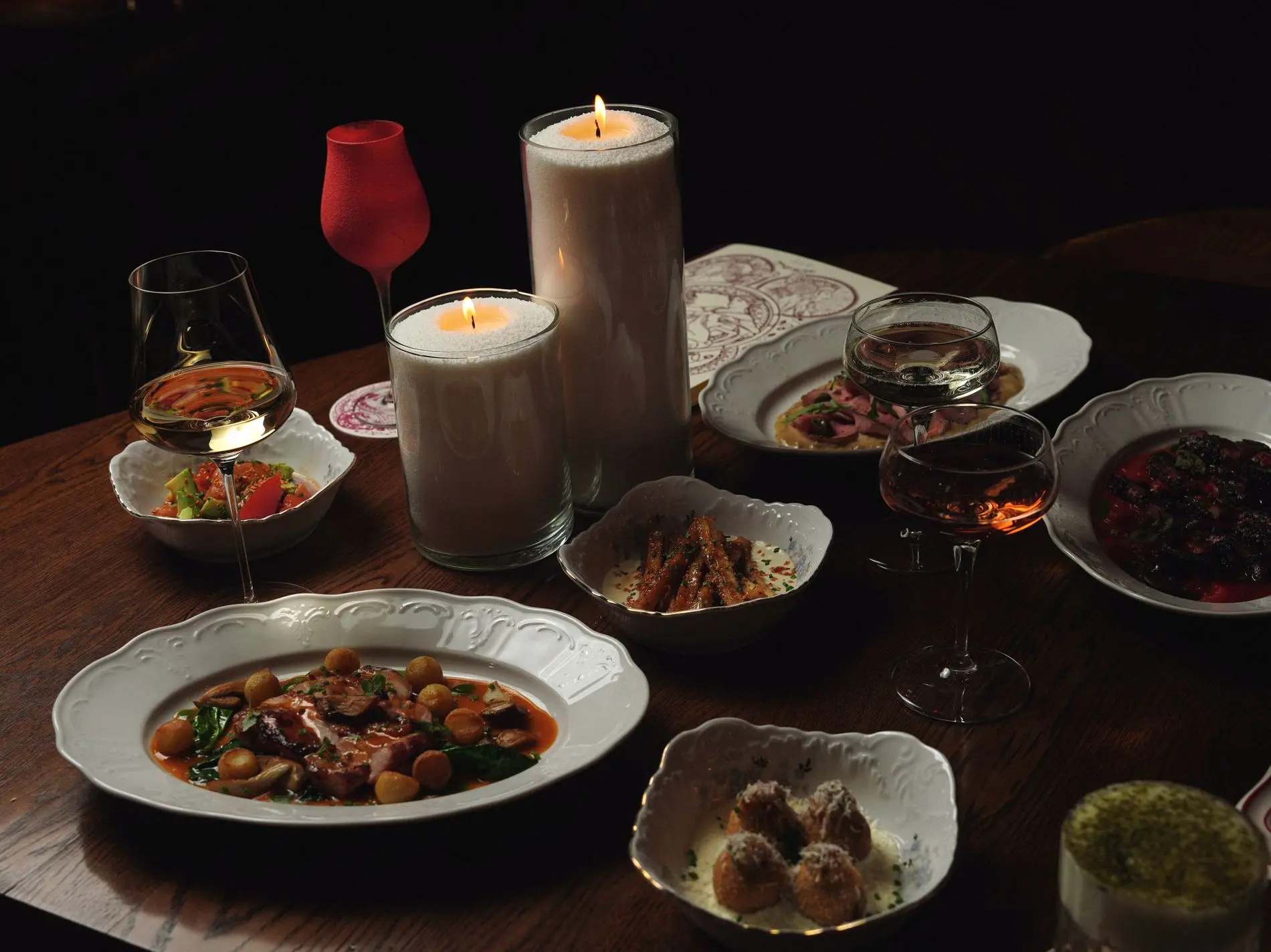 Mesa servida con platos de la casa a la luz de las velas
