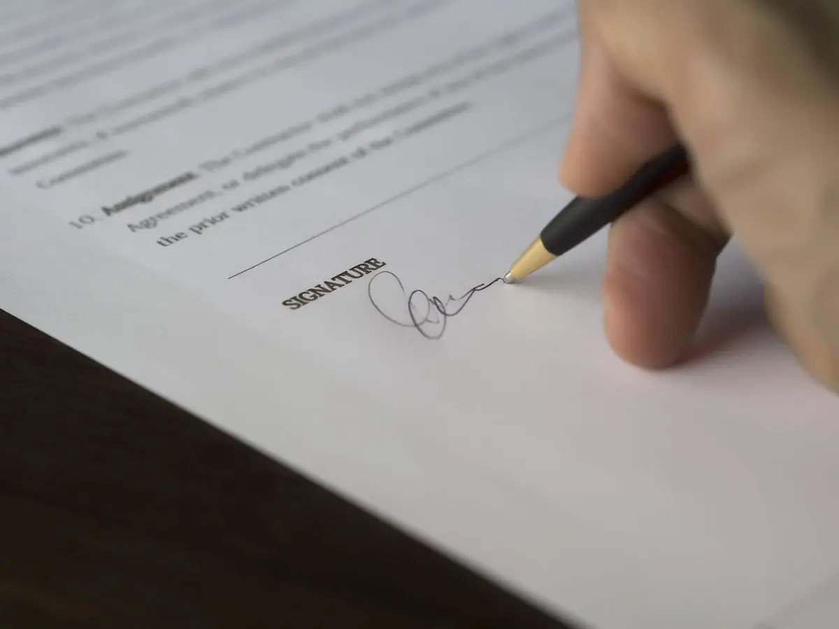 Mano firmando un contrato con bolígrafo